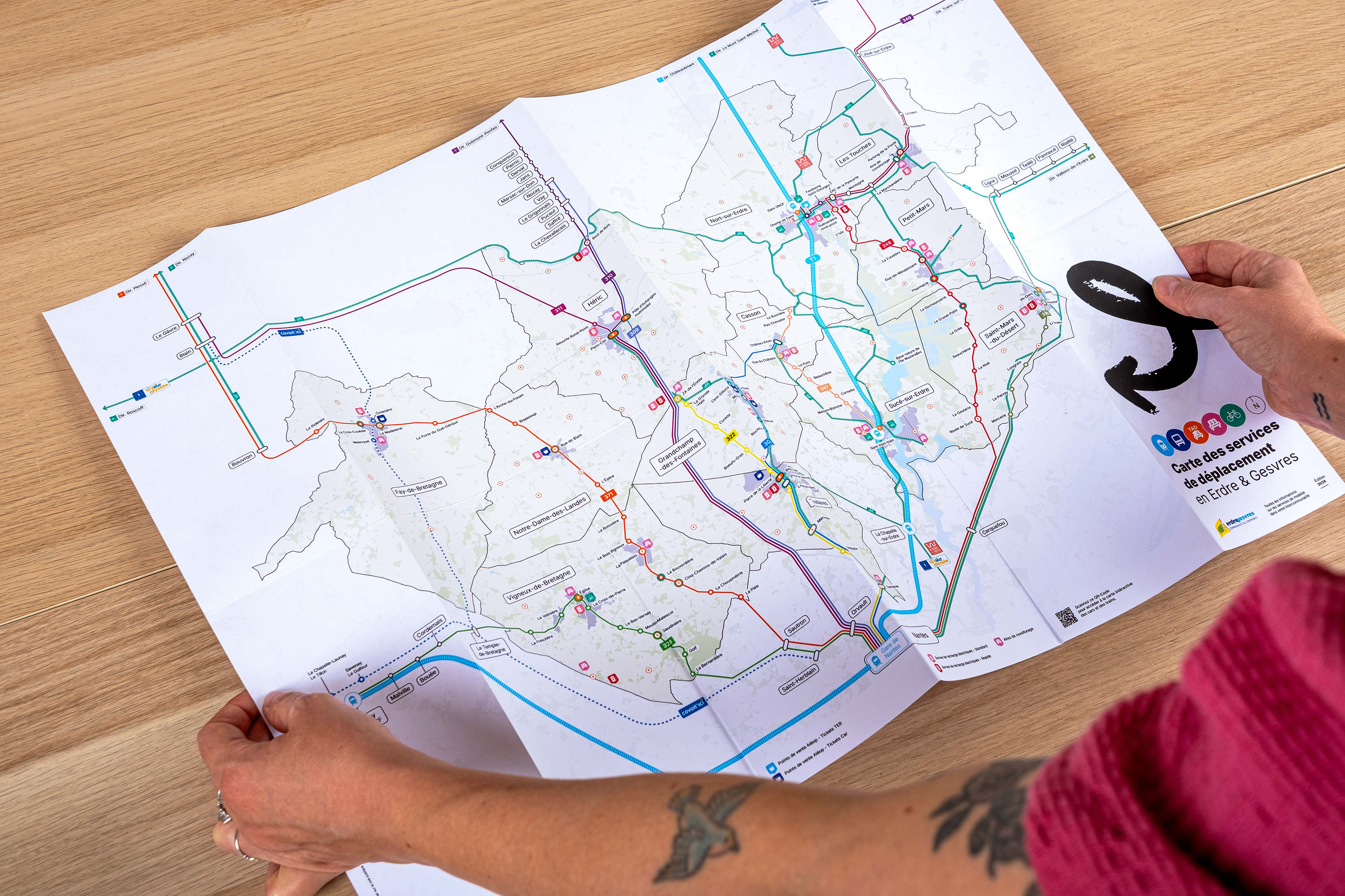 La carte des services de déplacement dépliée, tenue à deux mains, révélant le réseau de transports