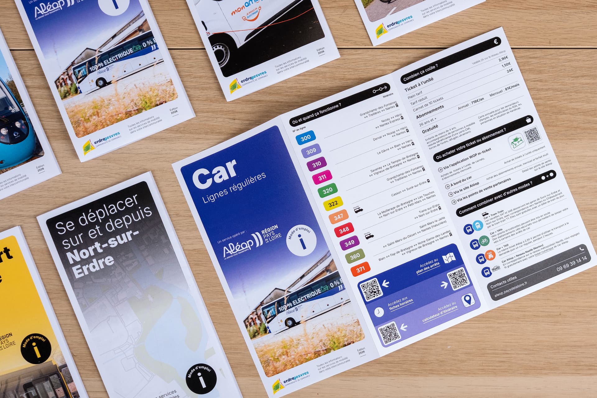 Les guides modulaires dépliés et posés sur un parquet : « Car Lignes régulières » et « Se déplacer sur et depuis Nort-sur-Erdre », accompagnés de leurs QR codes